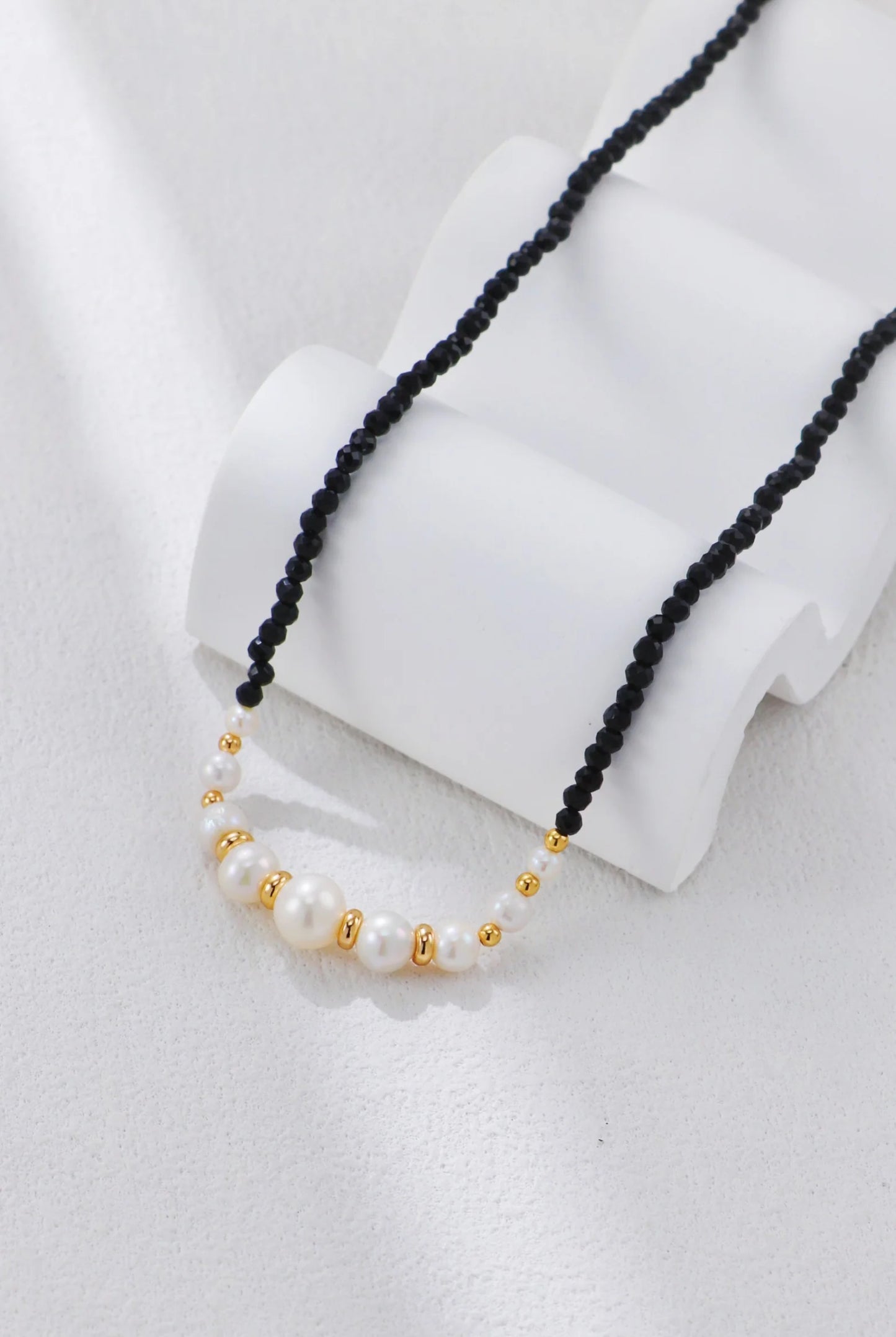 Collar con cuentas doradas y perla de espinela negra.